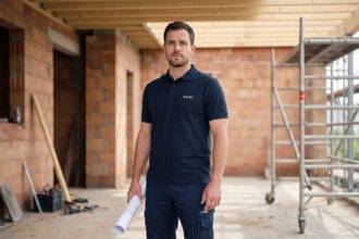 Artisan BTP portant une tenue de travail professionnelle Hakro polo et pantalon cargo sur un chantier de rénovation